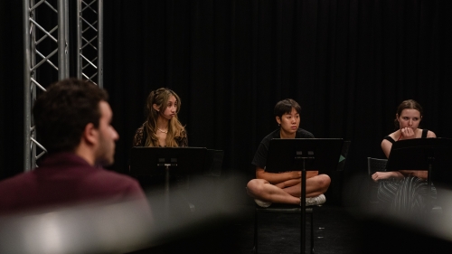 3 people sitting behind music stands listening to something off camera